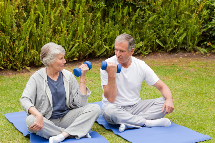Elderly couple exercising outdoors with dumbbells on yoga mats in the garden